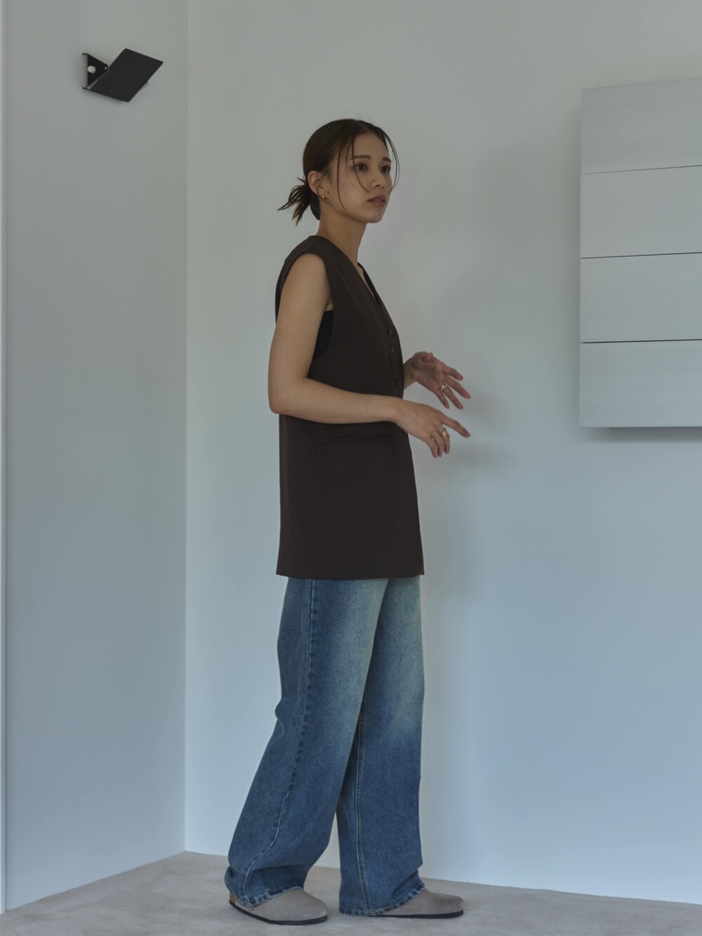 ブラウン系のベスト、ブルー系のデニムパンツ、ベージュ系のサンダルを着用したレディースの夏コーディネートの2枚目の写真