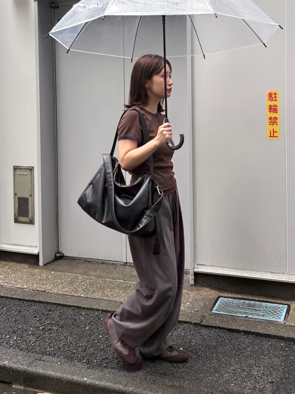 ブラウン系のTシャツ/カットソー、グレー系のスラックス、ブラック系のショルダーバッグを着用したレディースの夏コーディネートの2枚目の写真