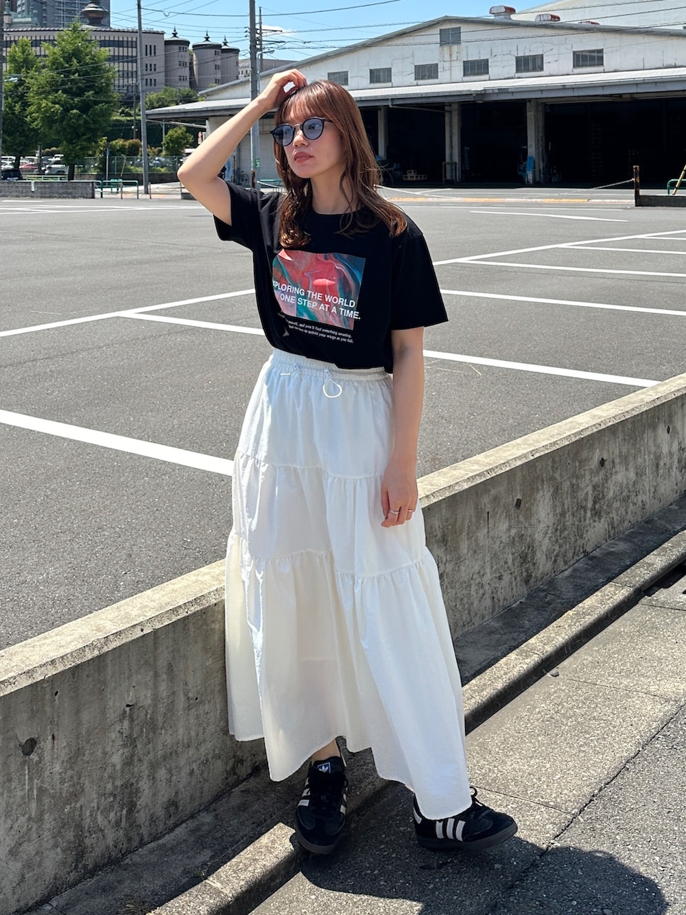 ブラック系のTシャツ/カットソー、ホワイト系のスカート、ブラック系のスニーカーを着用したレディースの夏コーディネートの2枚目の写真