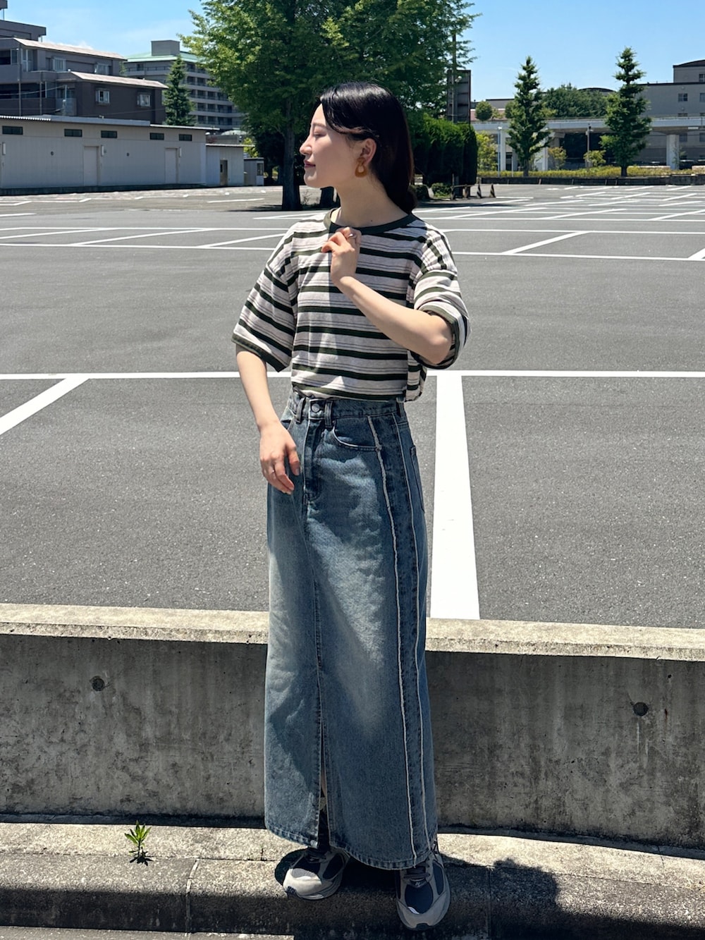 ブルー系のデニムスカート、グリーン系のTシャツ/カットソー、グレー系のスニーカーを着用したレディースの夏コーディネートの2枚目の写真