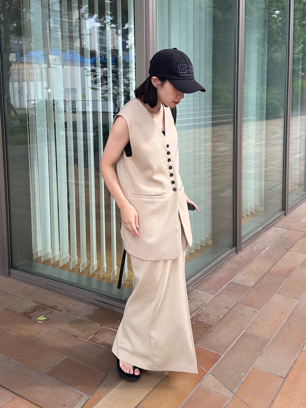 ホワイト系のベスト、ホワイト系のスカート、ブラック系のサンダルを着用したレディースの夏コーディネートの2枚目の写真