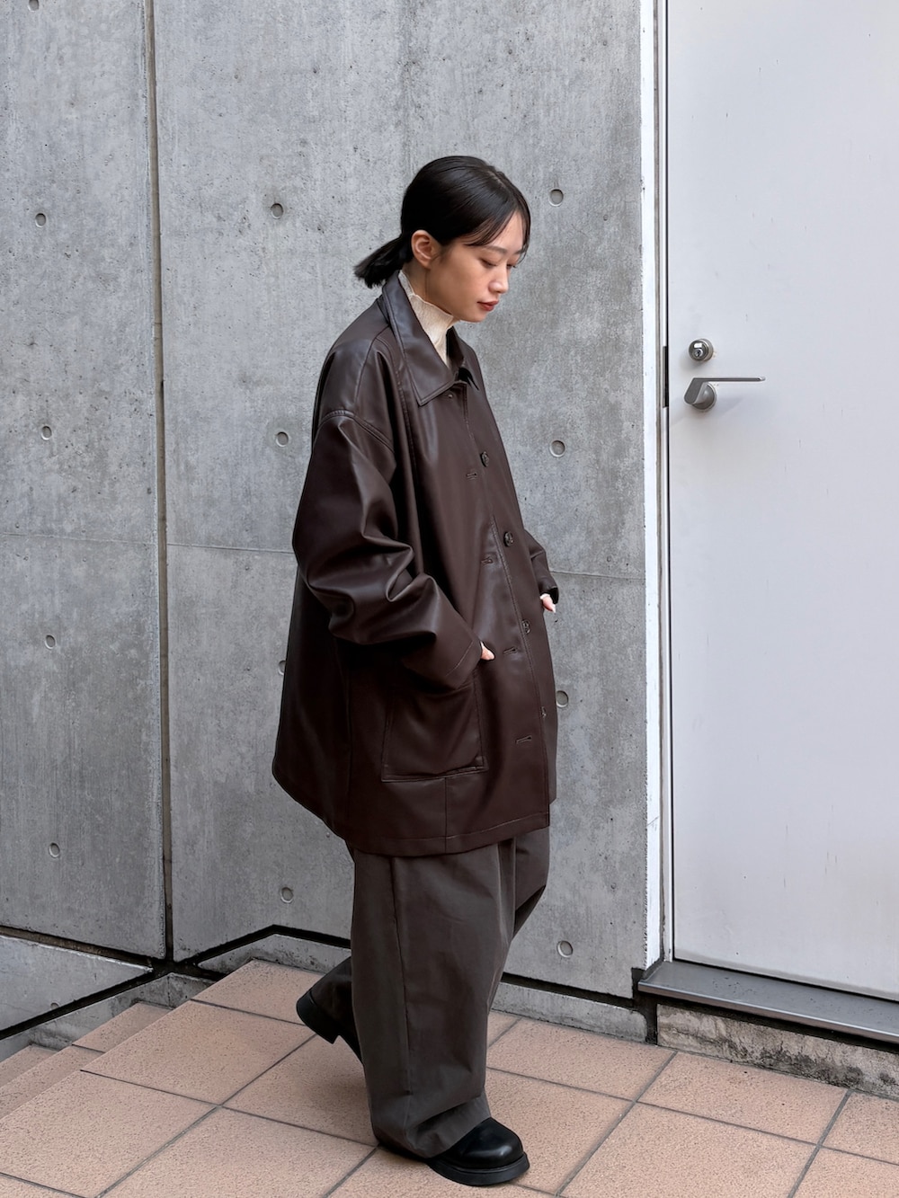 ブラウン系のカバーオール、ホワイト系のカーディガン/ボレロ、ブラック系のショルダーバッグを着用したレディースの春コーディネートの2枚目の写真