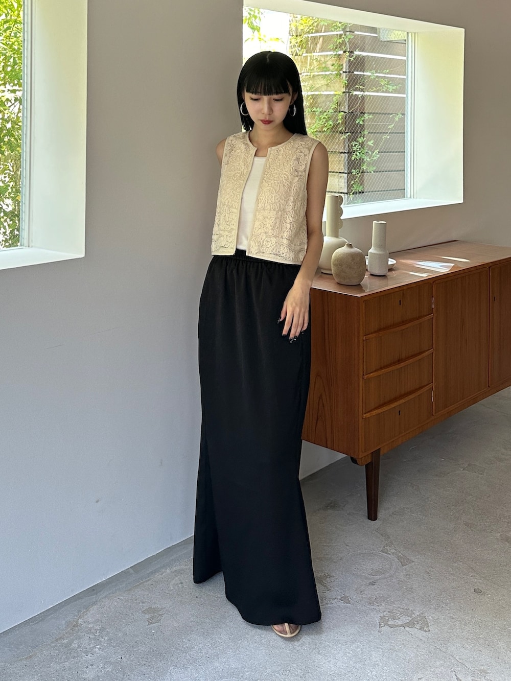 ホワイト系のベスト、ブラック系のスカート、ベージュ系のその他シューズを着用したレディースの夏コーディネートの2枚目の写真