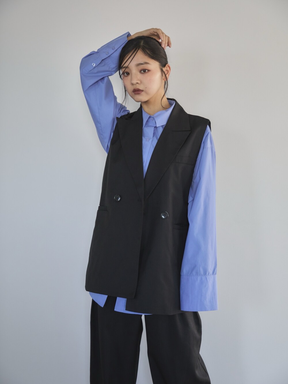 ブラック系のベスト、ブルー系のシャツ/ブラウス、ブラック系のスラックスを着用したレディースの冬コーディネートの4枚目の写真