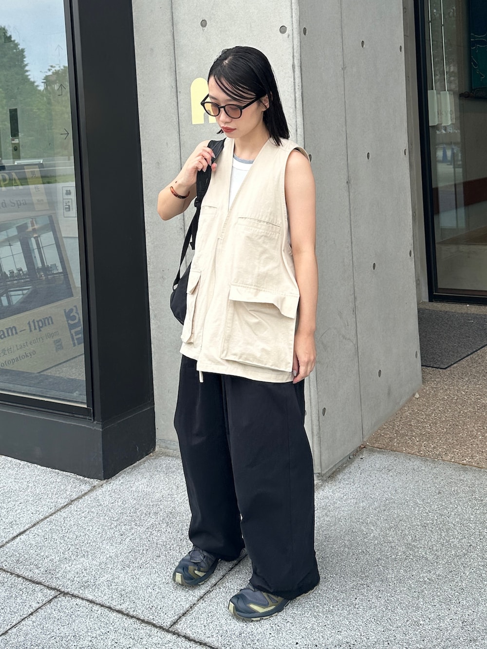ホワイト系のベスト、ブラック系のその他パンツ、グリーン系のスニーカーを着用したレディースの夏コーディネートの2枚目の写真
