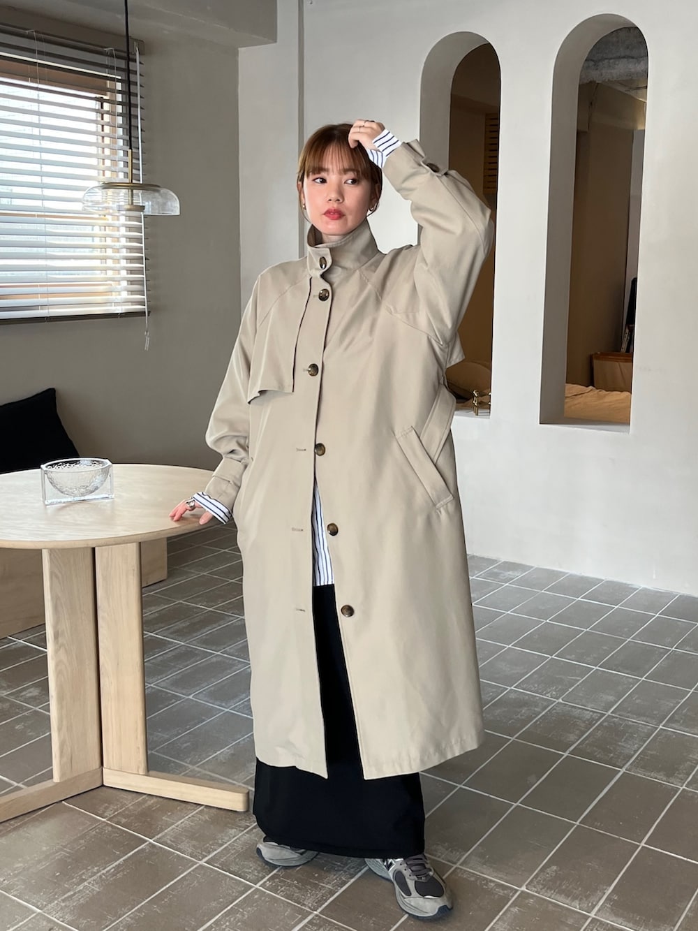 グリーン系のトレンチコート、ホワイト系のシャツ/ブラウス、ブラック系のスカートを着用したレディースの春コーディネートの2枚目の写真