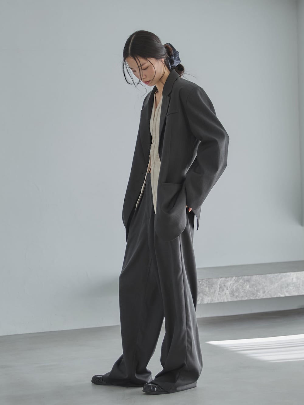 グレー系のテーラードジャケット、ホワイト系のカーディガン/ボレロ、グレー系のスラックスを着用したレディースの冬コーディネートの2枚目の写真