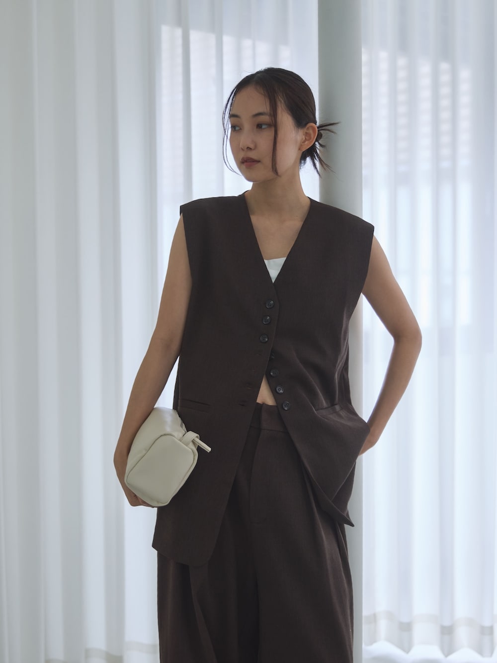 ブラウン系のベスト、ブラウン系のスラックス、ブラック系のサンダルを着用したレディースの夏コーディネートの4枚目の写真