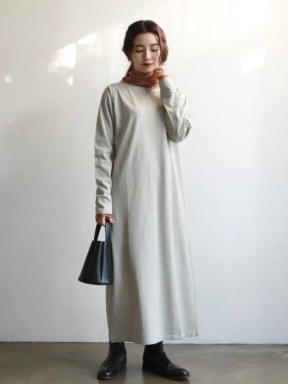 ベージュ系のワンピース、ブラウン系のハンドバッグ、ゴールド系のバレエシューズを着用したレディースの冬コーディネートの2枚目の写真