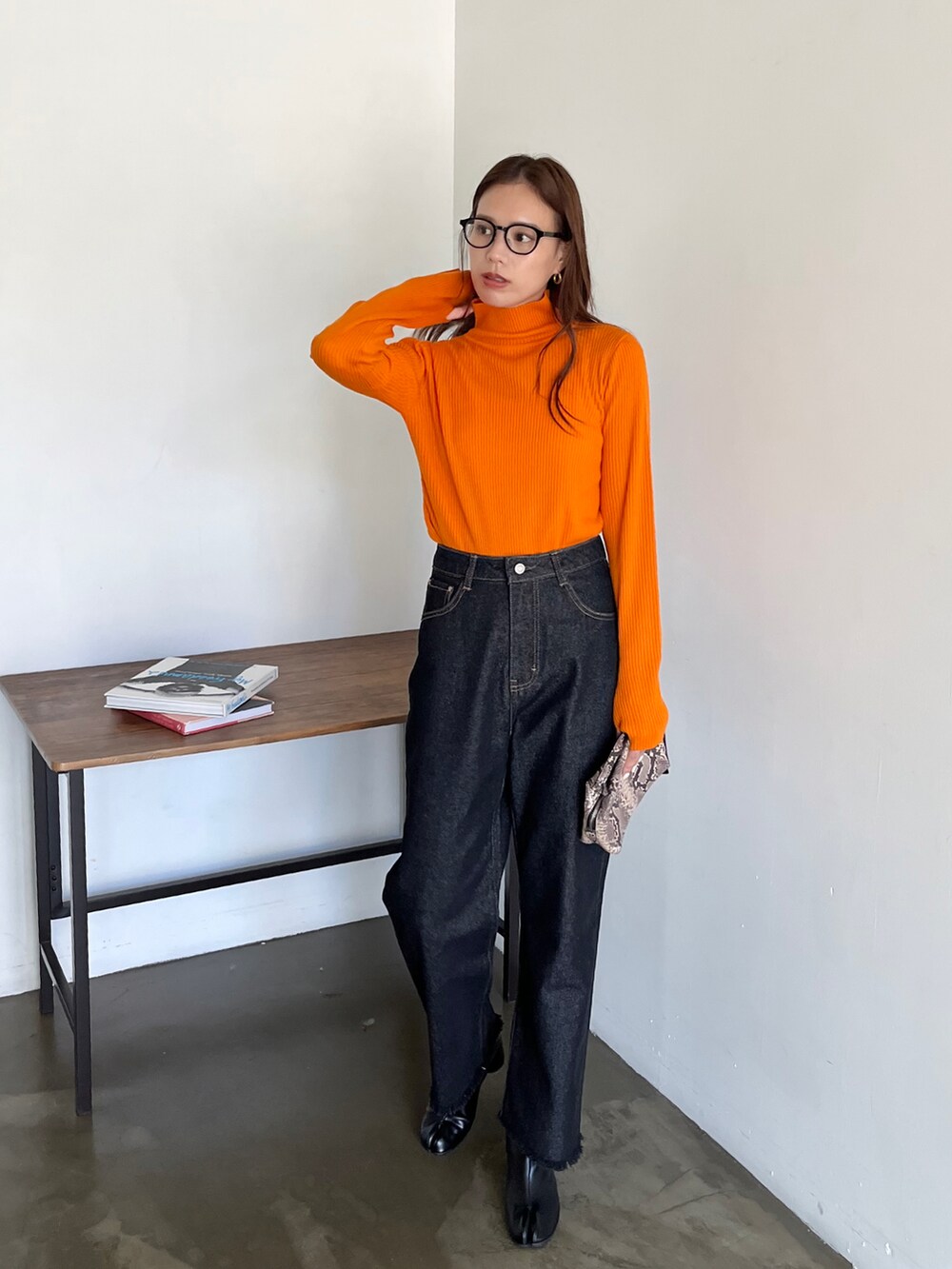 ブラック系のデニムパンツ、その他のショルダーバッグ、オレンジ系のニット/セーターを着用したレディースの秋コーディネートの2枚目の写真