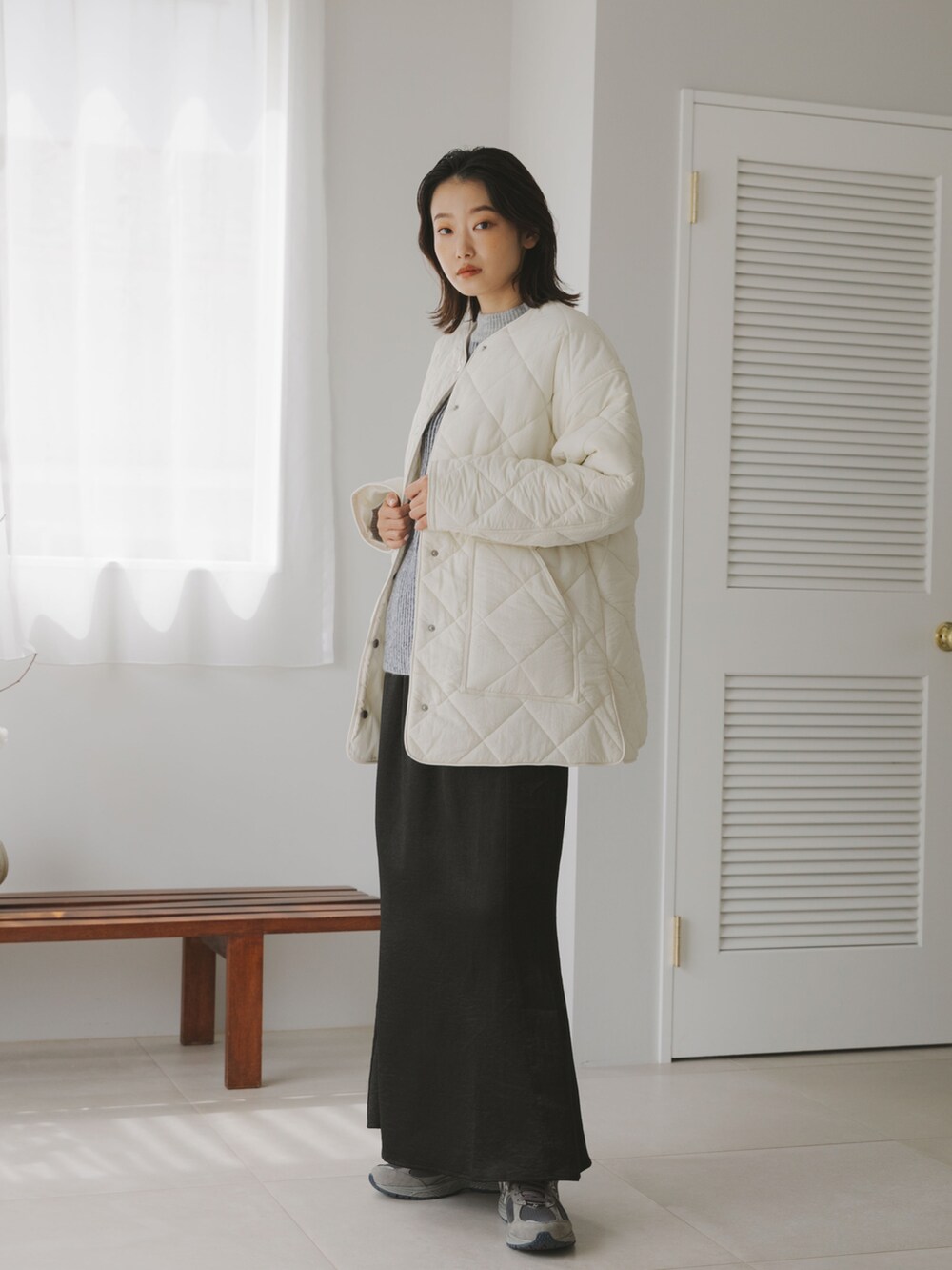 グレー系のスニーカー、ブラック系のスカート、グレー系のニット/セーターを着用したレディースの秋コーディネートの2枚目の写真