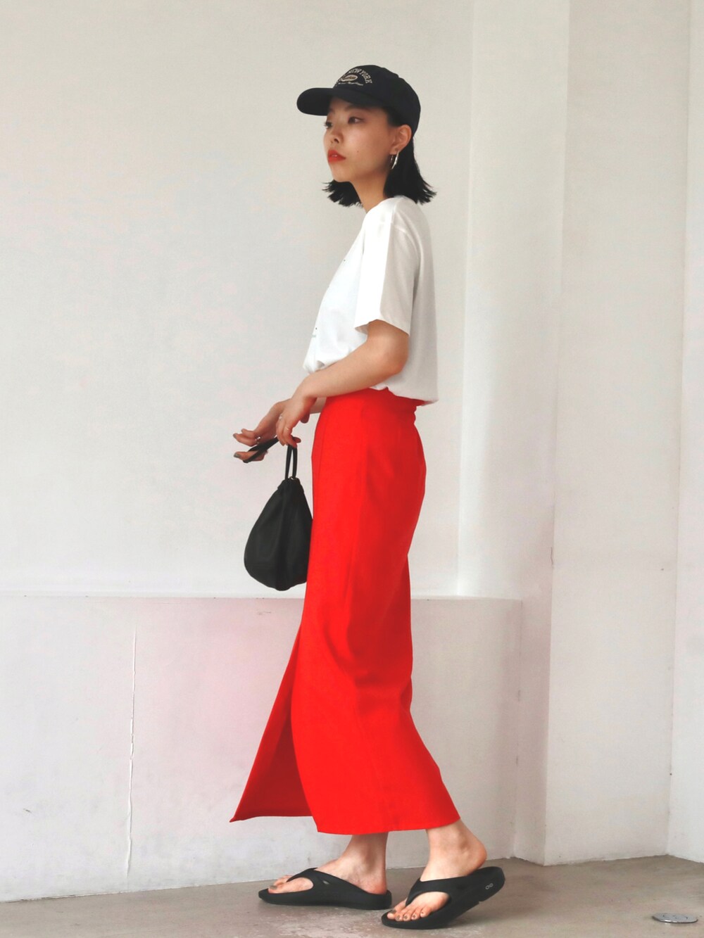 ブラック系のハンドバッグ、レッド系のスカート、ホワイト系のTシャツ/カットソーを着用したレディースの夏コーディネートの2枚目の写真