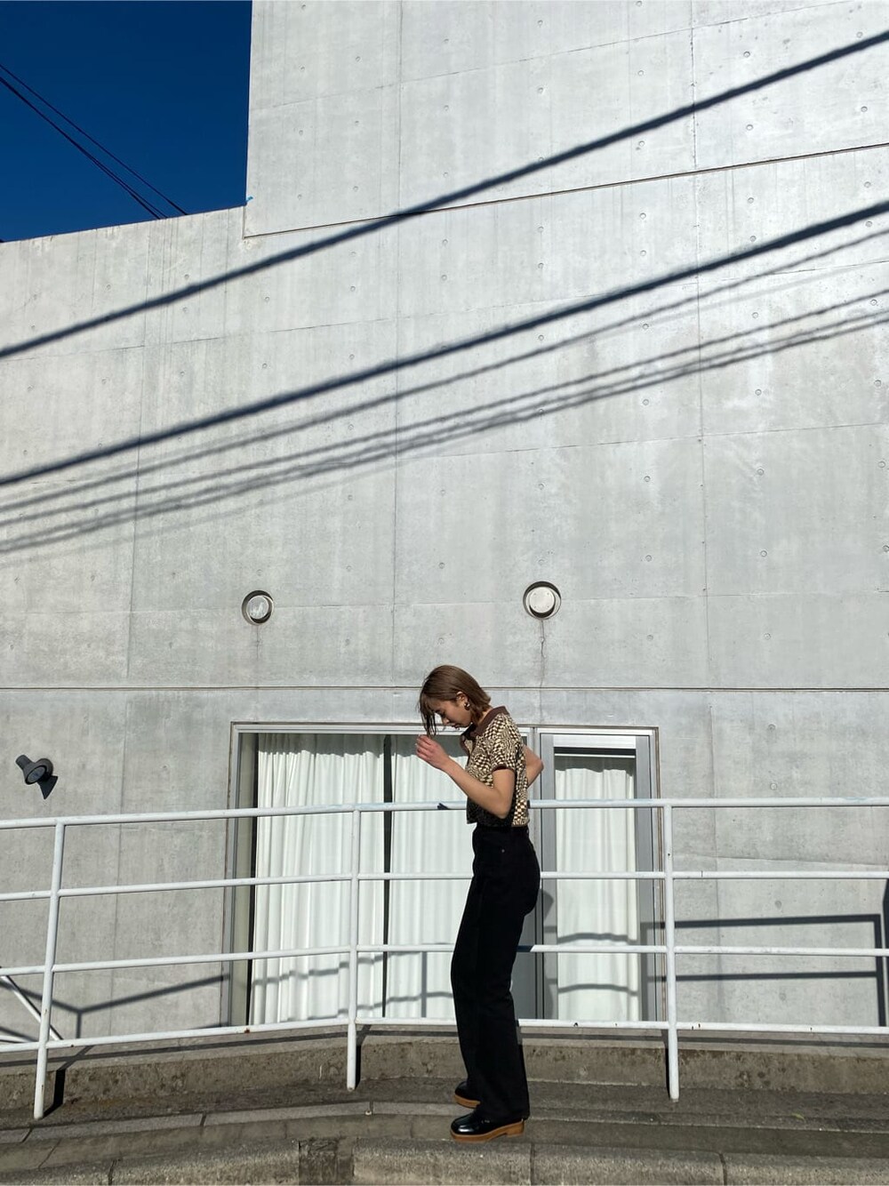 ブラック系のローファー、その他のポロシャツ、ブラック系のデニムパンツを着用したレディースの冬コーディネートの2枚目の写真