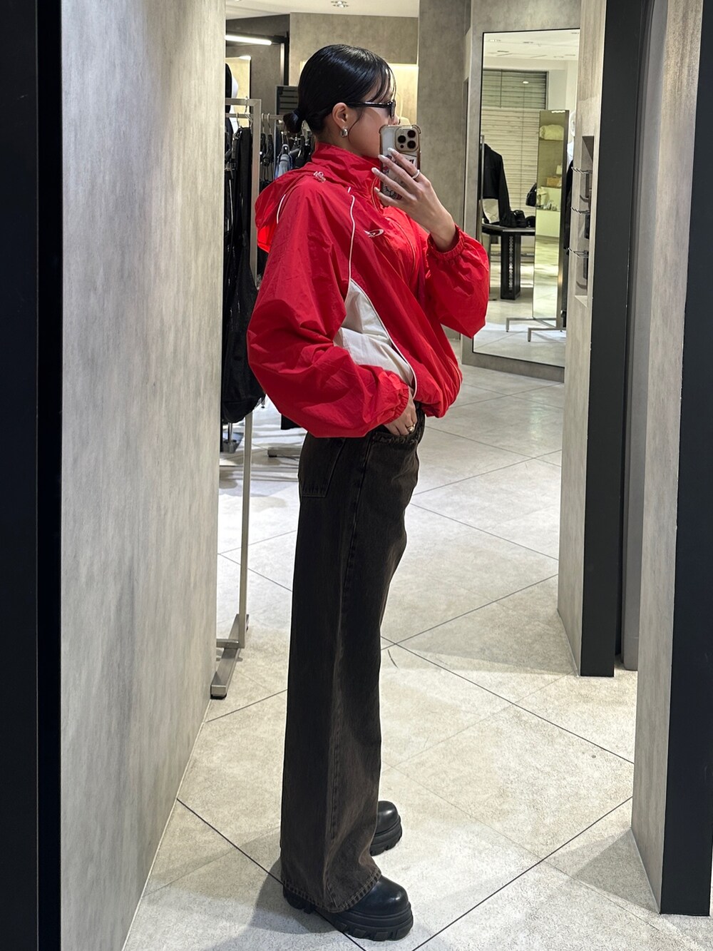 レッド系のブルゾン、ブラック系のデニムパンツ、ブラック系のブーツを着用したレディースの春コーディネートの2枚目の写真