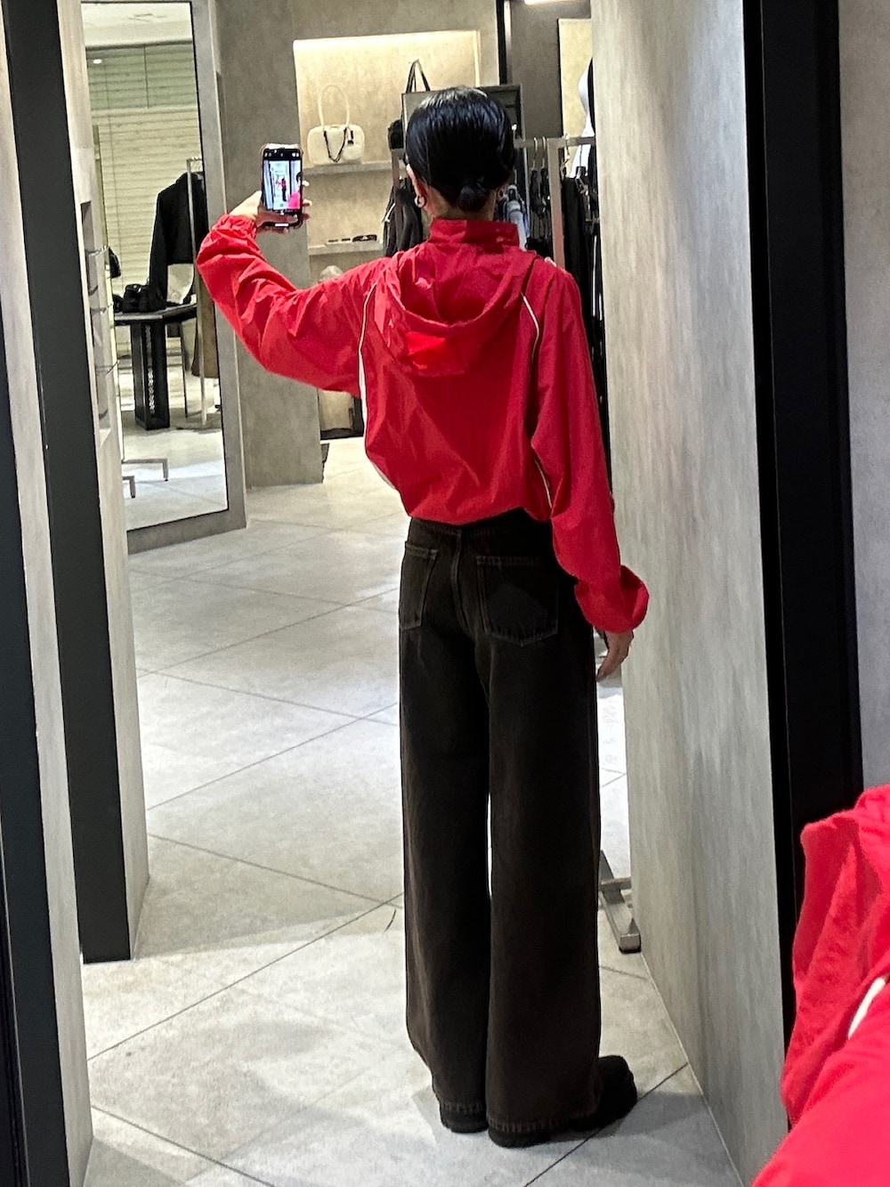 レッド系のブルゾン、ブラック系のデニムパンツ、ブラック系のブーツを着用したレディースの春コーディネートの3枚目の写真