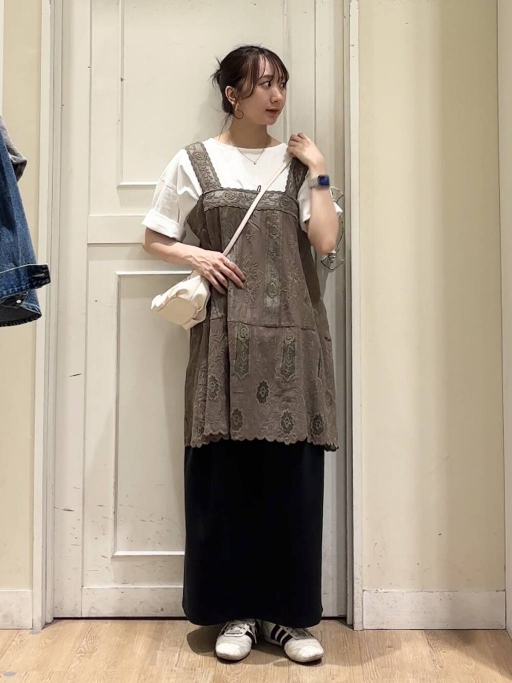 ベージュ系のショルダーバッグ、ブラック系のスカート、ホワイト系のTシャツ/カットソーを着用したレディースの春コーディネートの2枚目の写真