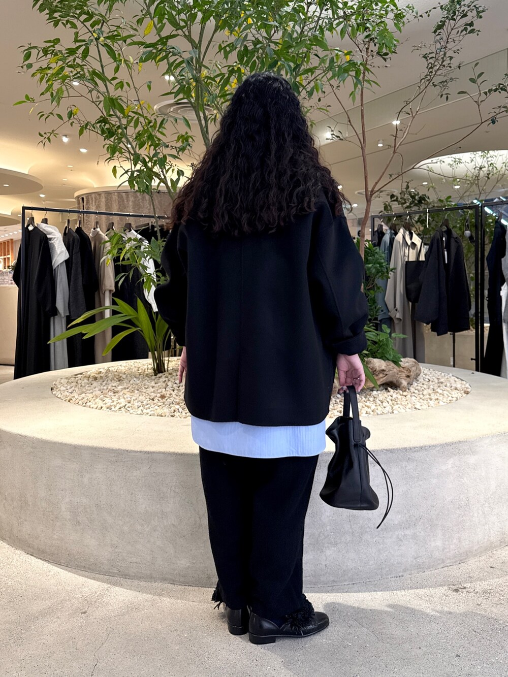 ブラック系のバッグ、ブラック系のその他アウター、ブラック系のTシャツ/カットソーを着用したレディースの冬コーディネートの3枚目の写真