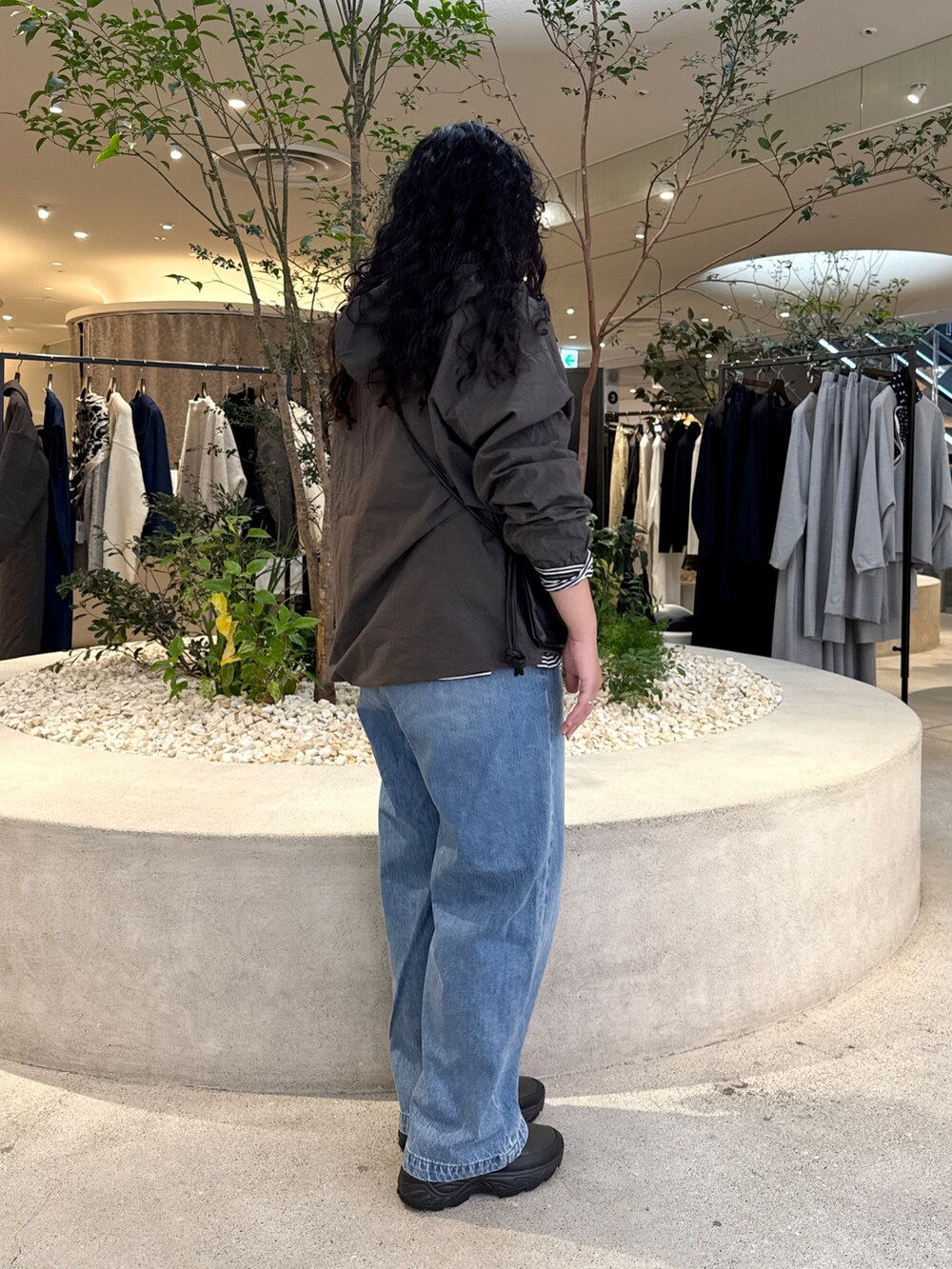 ブラック系のショルダーバッグ、ブルー系のデニムパンツ、グレー系のTシャツ/カットソーを着用したレディースの秋コーディネートの2枚目の写真