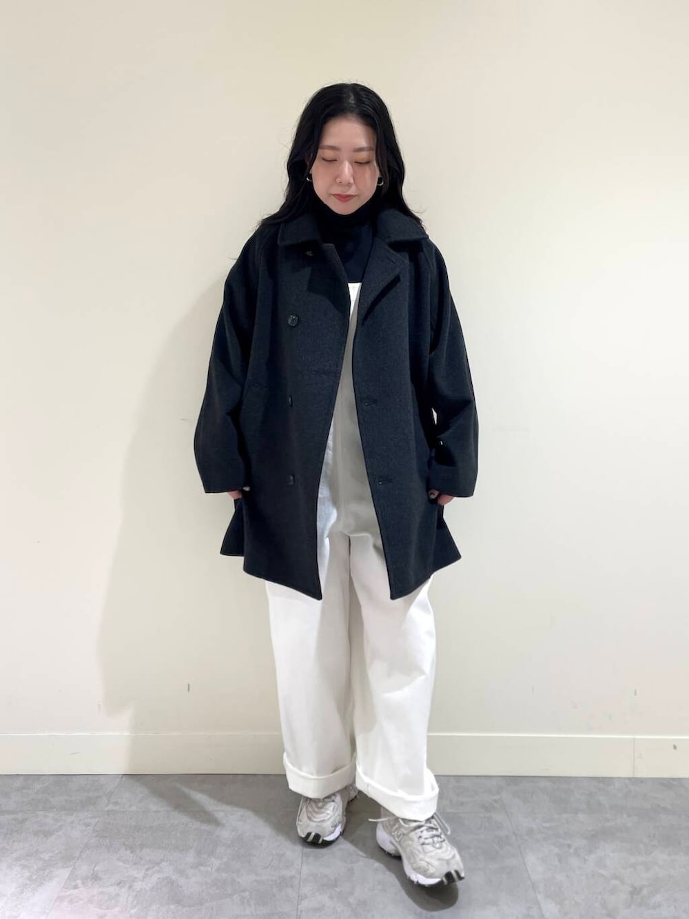 グレー系のピーコート、ホワイト系のサロペット/オーバーオール、ブラック系のTシャツ/カットソーを着用したレディースの秋コーディネートの2枚目の写真