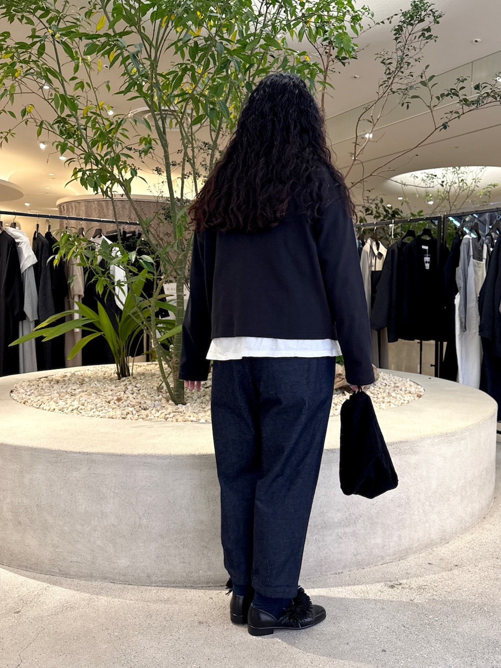 ブラック系のショルダーバッグ、ブラック系のドレスシューズ、ブルー系のデニムパンツを着用したレディースの冬コーディネートの3枚目の写真