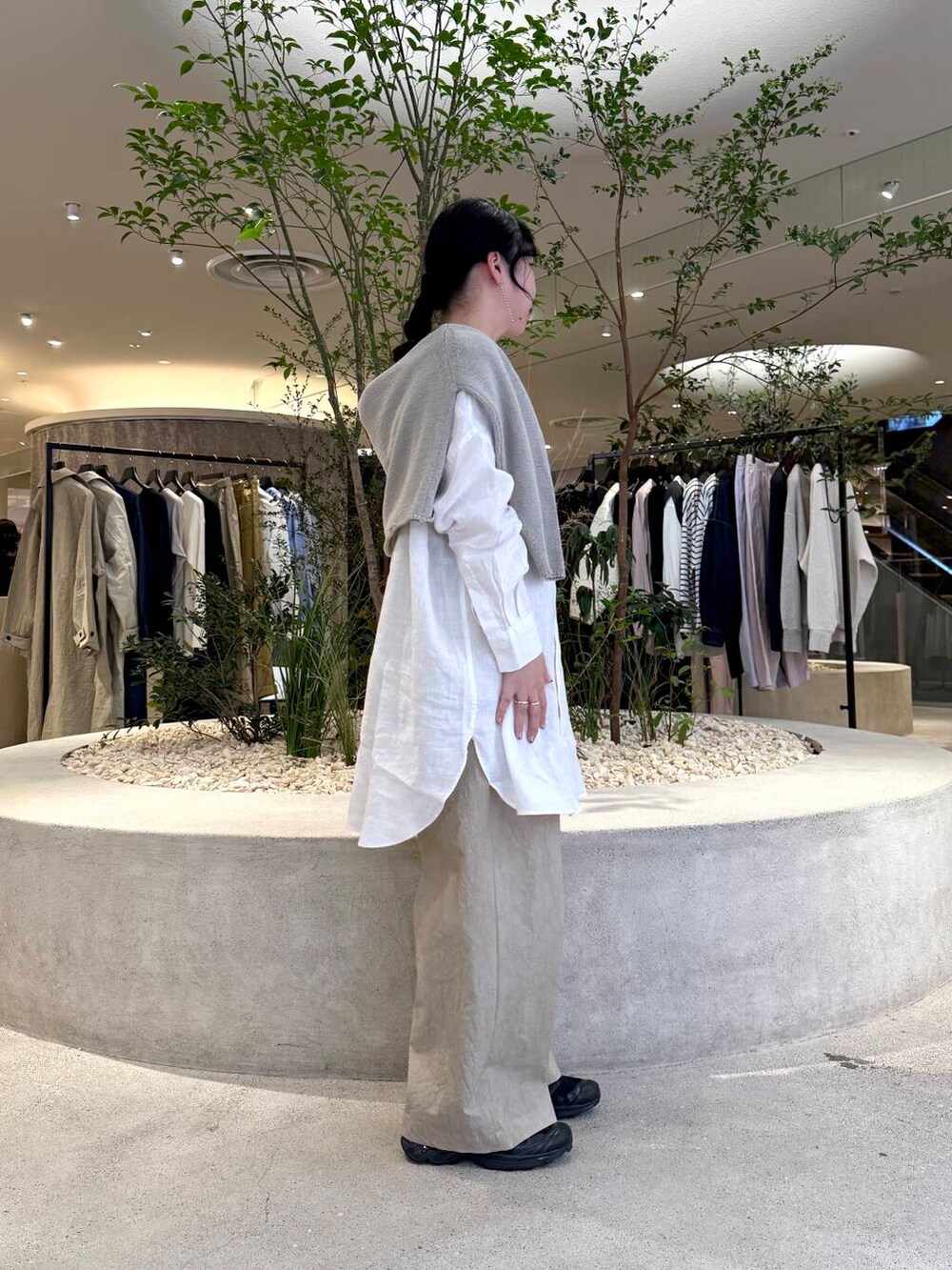グレー系のニット/セーター、ホワイト系のシャツ/ブラウス、ベージュ系のその他パンツを着用したレディースの春コーディネートの2枚目の写真