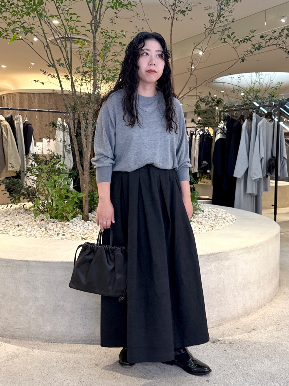 グレー系のニット/セーター、ブラック系のスカート、ブラック系のバッグを着用したレディースの秋コーディネートの4枚目の写真