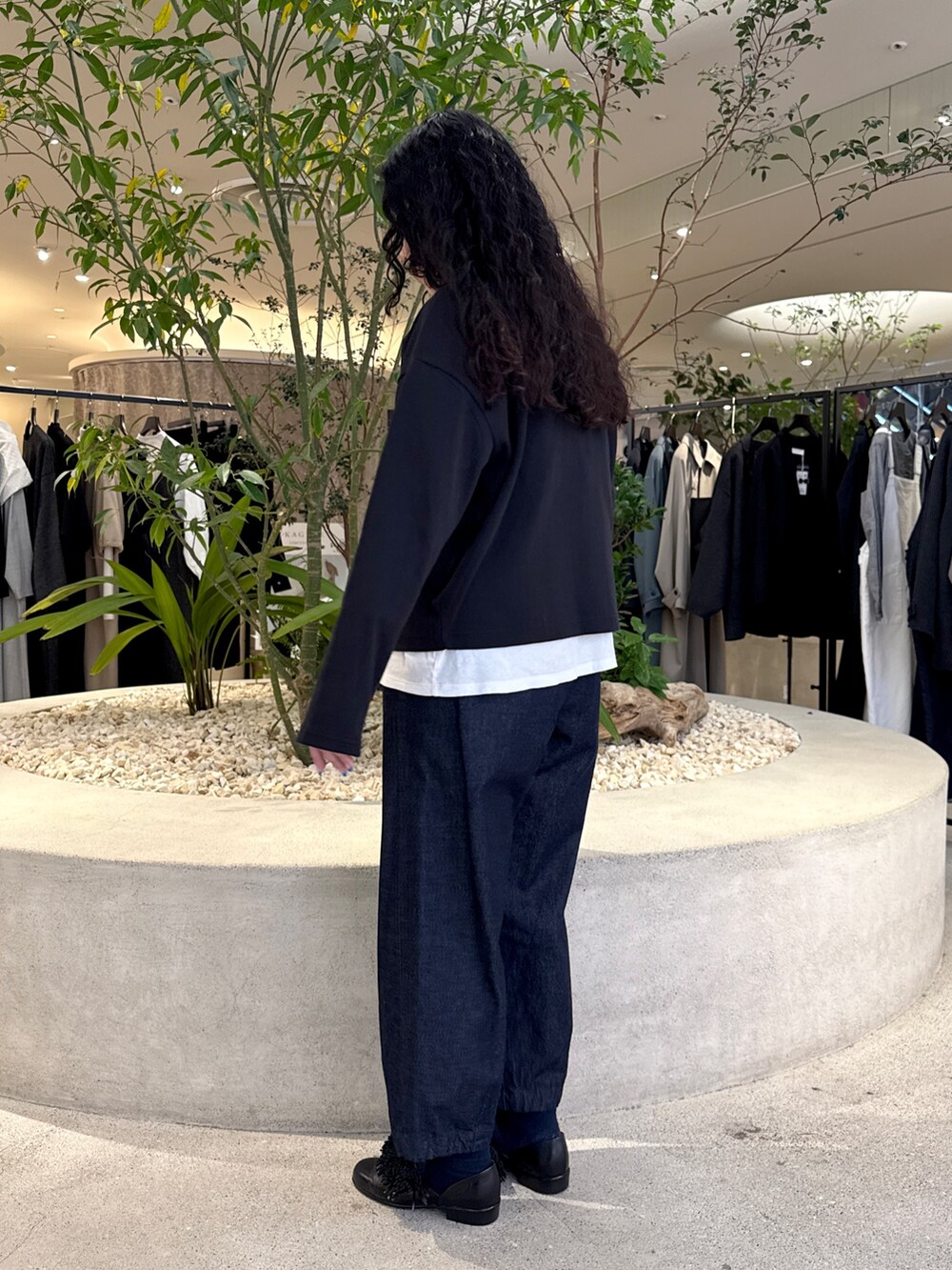 ブラック系のショルダーバッグ、ブラック系のドレスシューズ、ブルー系のデニムパンツを着用したレディースの冬コーディネートの4枚目の写真