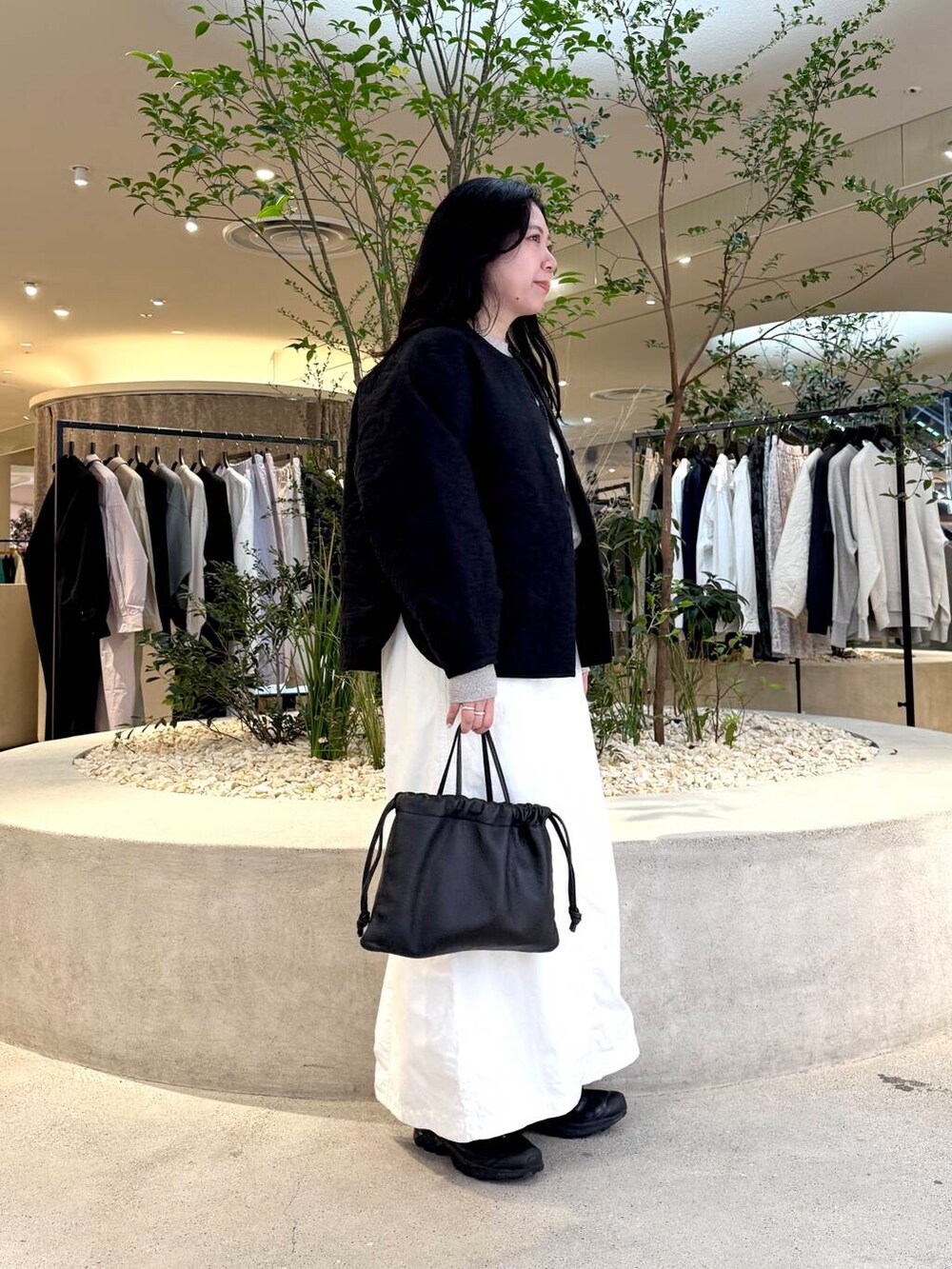 ホワイト系のスカート、グレー系のスウェット、ブラック系のダウンジャケット/コートを着用したレディースの春コーディネートの2枚目の写真