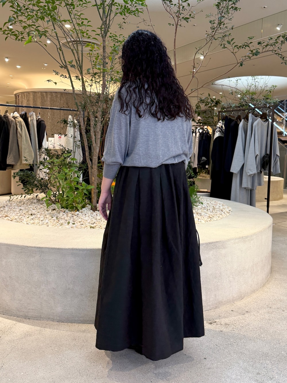 グレー系のニット/セーター、ブラック系のスカート、ブラック系のバッグを着用したレディースの秋コーディネートの3枚目の写真