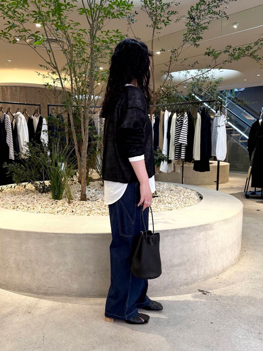 ホワイト系のTシャツ/カットソー、ブルー系のデニムパンツ、ブラック系のニット/セーターを着用したレディースの春コーディネートの2枚目の写真