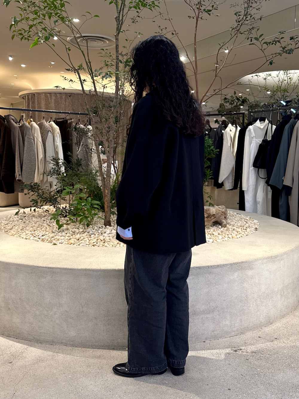 グレー系のニット/セーター、ブラック系のその他アウター、ブルー系のシャツ/ブラウスを着用したレディースの秋コーディネートの3枚目の写真