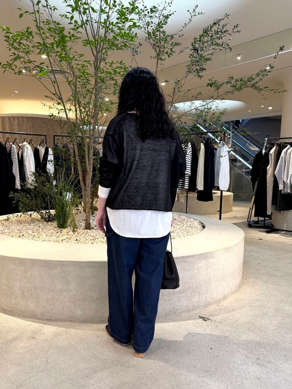 ホワイト系のTシャツ/カットソー、ブルー系のデニムパンツ、ブラック系のニット/セーターを着用したレディースの春コーディネートの3枚目の写真