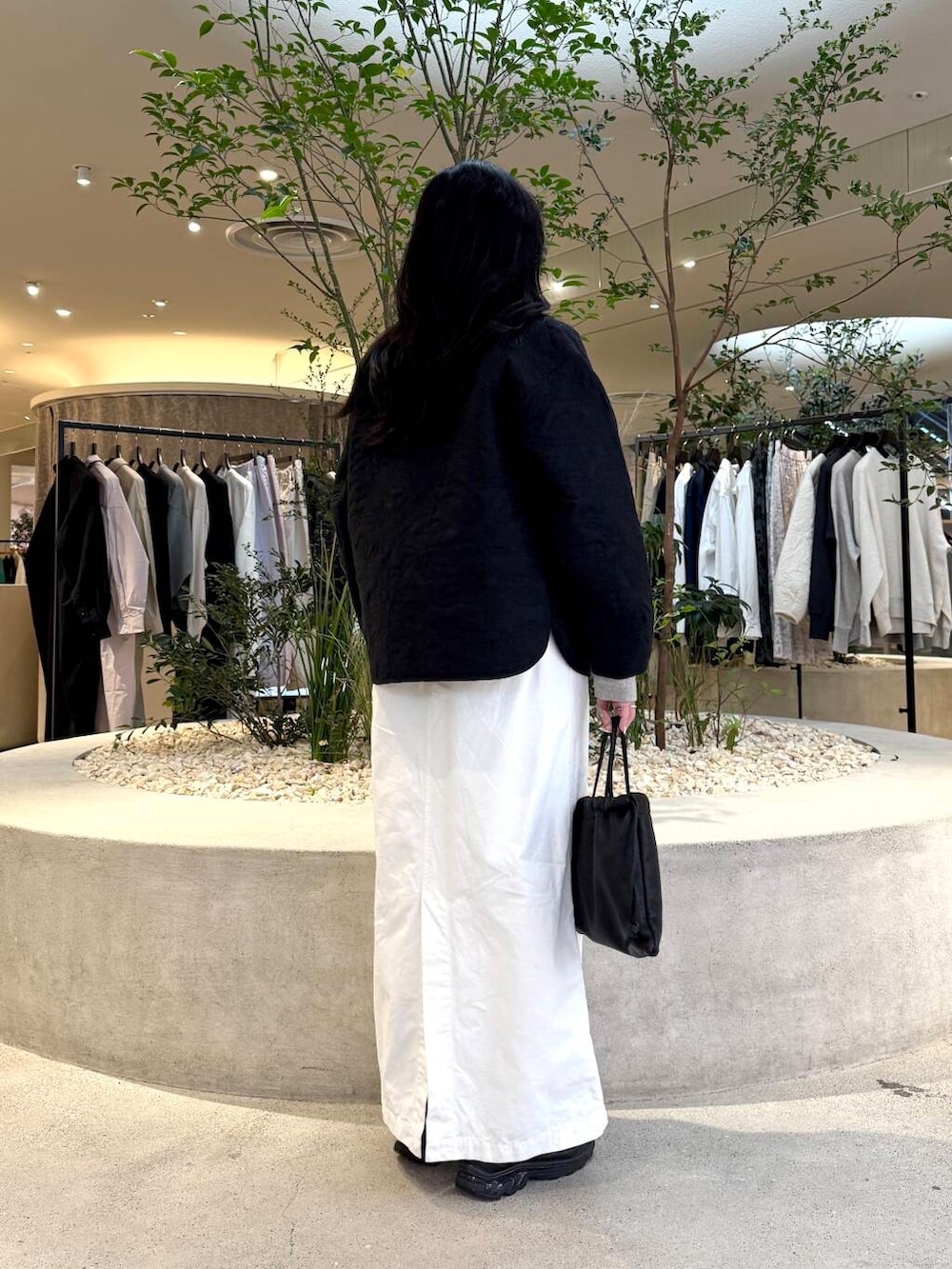 ホワイト系のスカート、グレー系のスウェット、ブラック系のダウンジャケット/コートを着用したレディースの春コーディネートの3枚目の写真