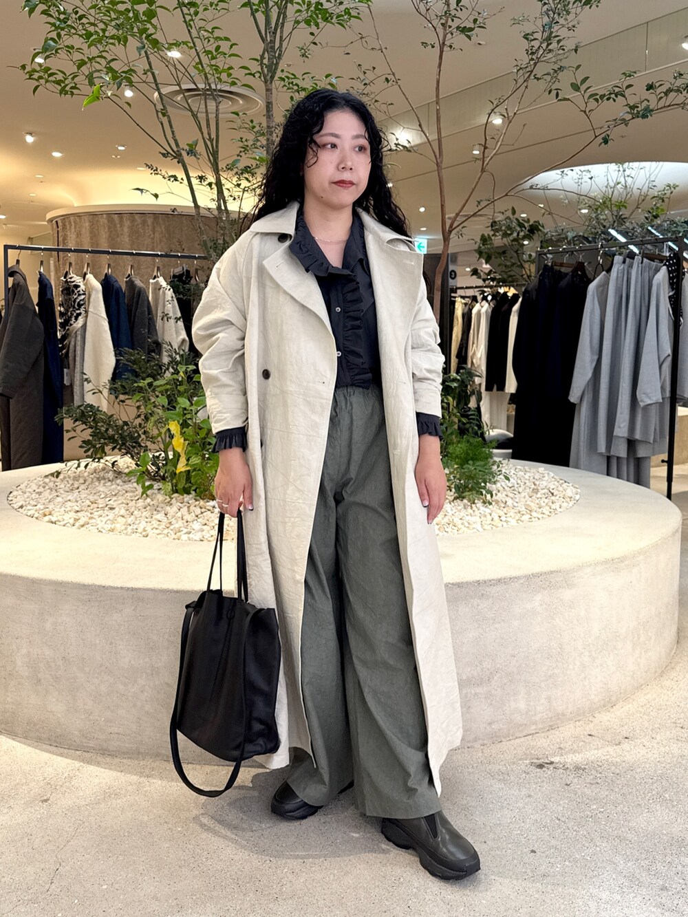 ブラック系のトートバッグ、グリーン系のその他パンツ、ベージュ系のトレンチコートを着用したレディースの秋コーディネートの4枚目の写真