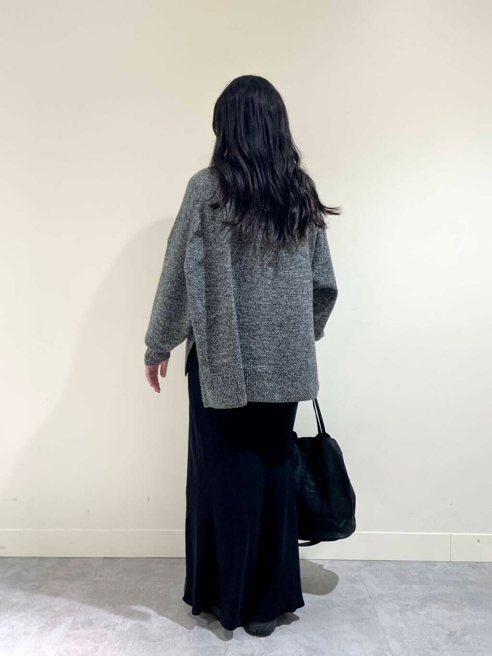 ブラック系のスカート、グレー系のニット/セーター、ブラック系のトートバッグを着用したレディースの冬コーディネートの4枚目の写真