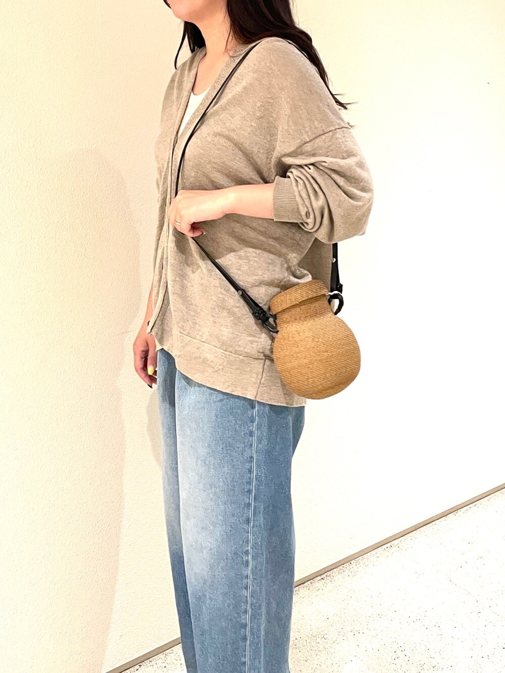 ベージュ系のカーディガン/ボレロ、ブルー系のデニムパンツ、ベージュ系のショルダーバッグを着用したレディースの夏コーディネートの3枚目の写真