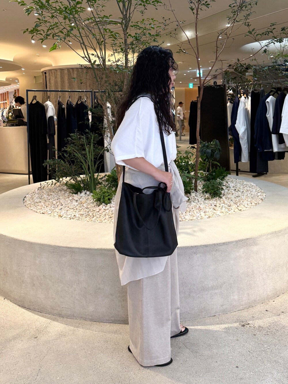 ベージュ系のその他パンツ、グレー系のシャツ/ブラウス、ブラック系のトートバッグを着用したレディースの夏コーディネートの2枚目の写真