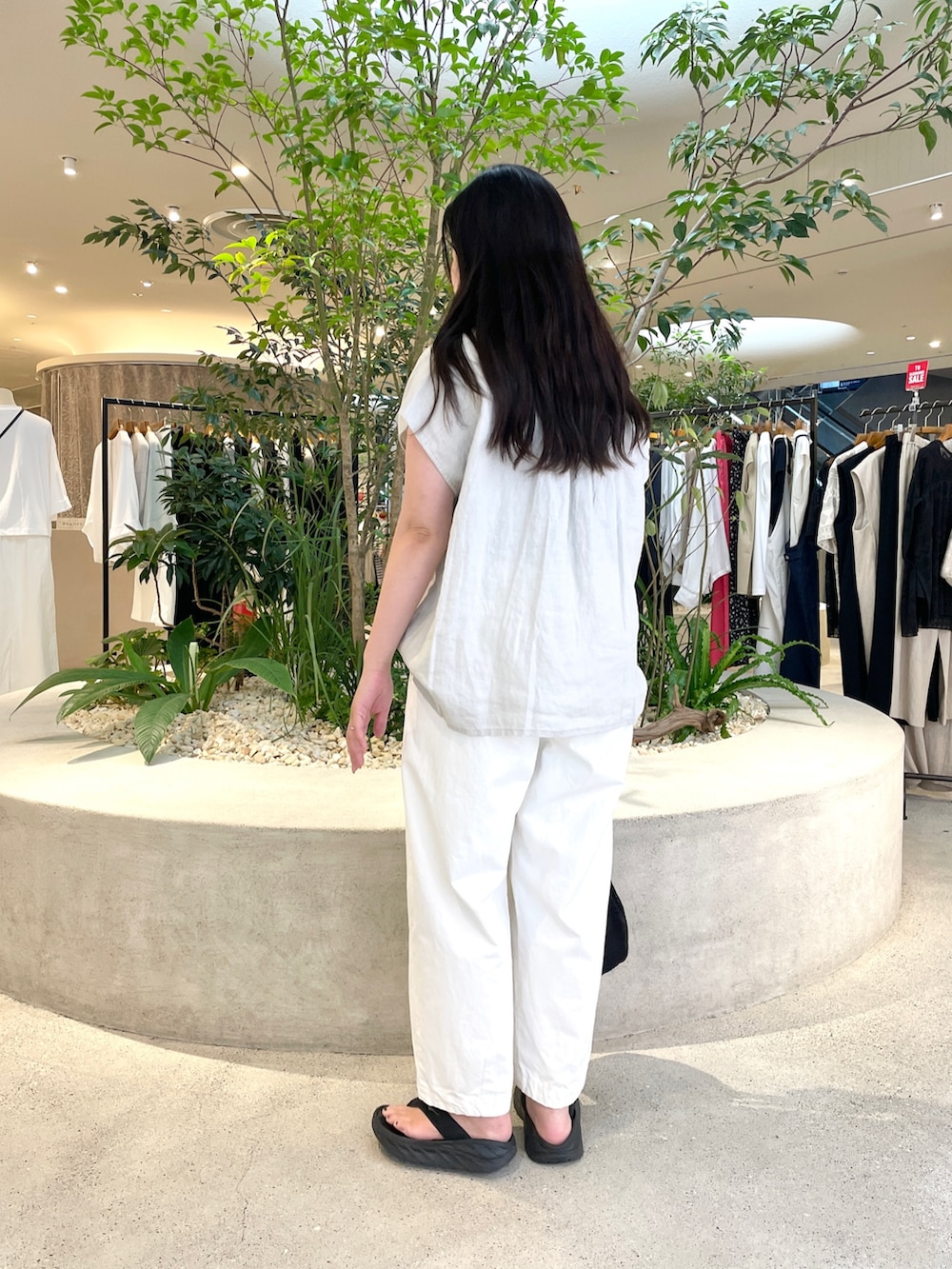 ブラック系のショルダーバッグ、ブラック系のサンダル、グレー系のTシャツ/カットソーを着用したレディースの夏コーディネートの2枚目の写真