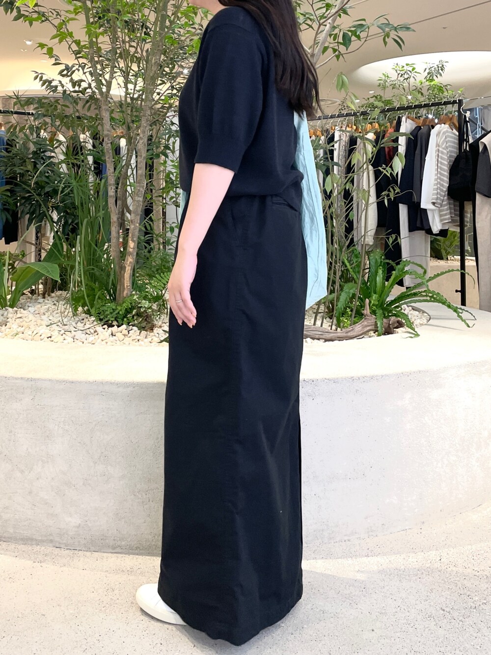 グリーン系のショルダーバッグ、ブラック系のニット/セーター、ブラック系のスカートを着用したレディースの夏コーディネートの2枚目の写真