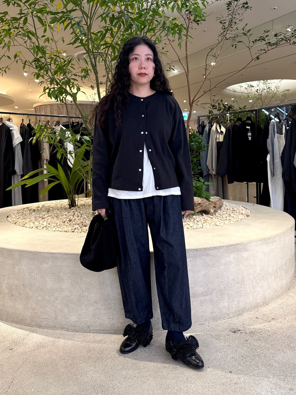 ブラック系のショルダーバッグ、ブラック系のドレスシューズ、ブルー系のデニムパンツを着用したレディースの冬コーディネートの5枚目の写真
