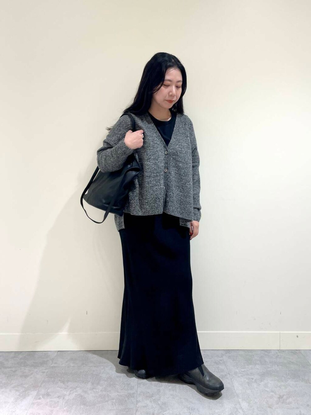 ブラック系のスカート、グレー系のニット/セーター、ブラック系のトートバッグを着用したレディースの冬コーディネートの2枚目の写真