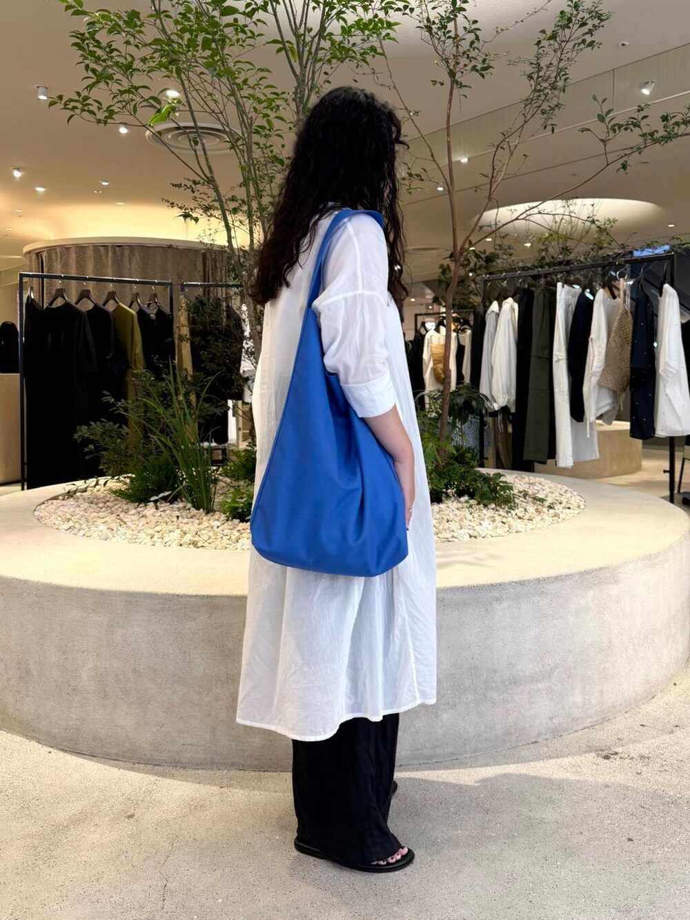 ブラック系のその他パンツ、ブラック系のサンダル、ブルー系のトートバッグを着用したレディースの夏コーディネートの2枚目の写真