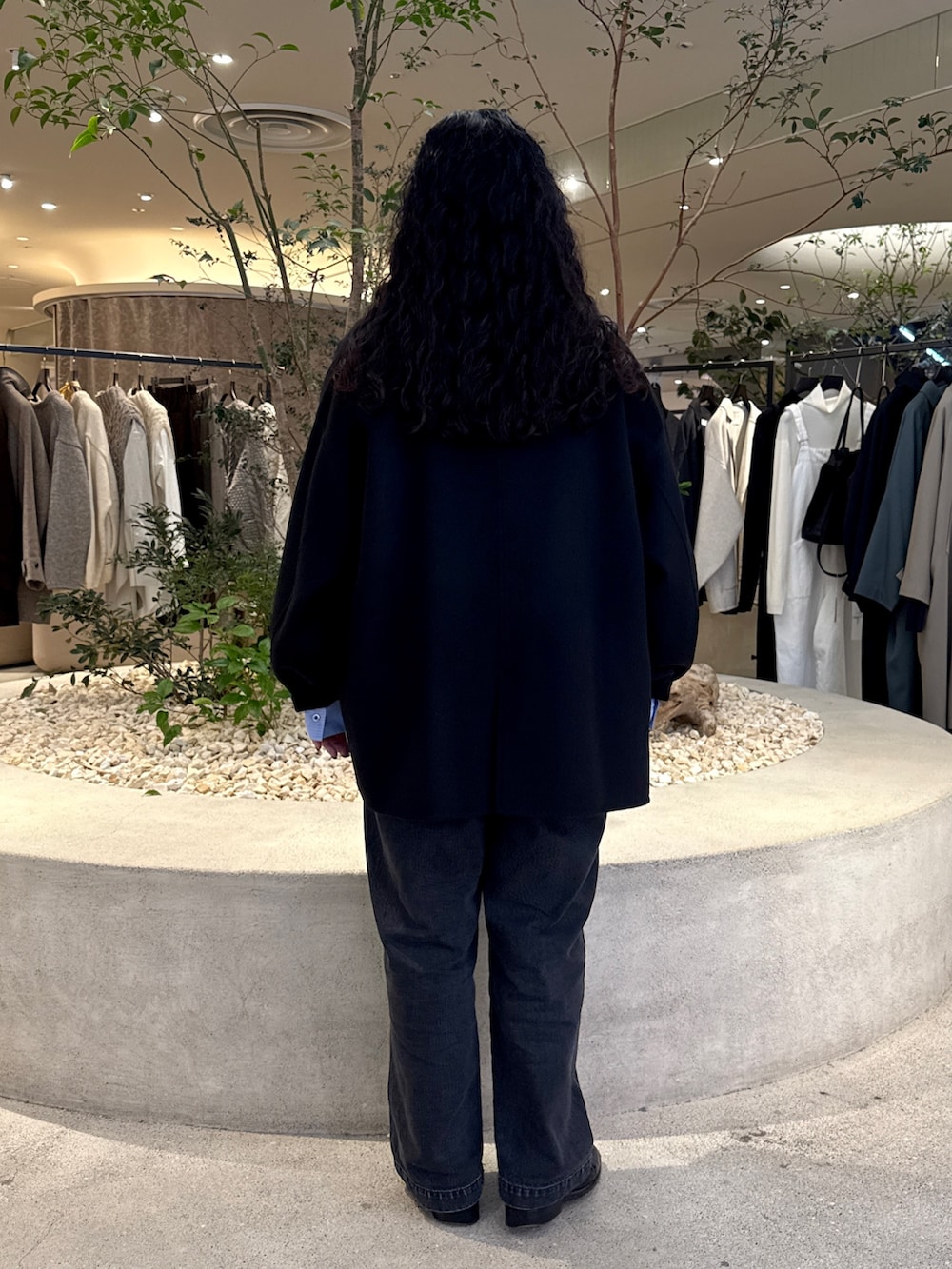 グレー系のニット/セーター、ブラック系のその他アウター、ブルー系のシャツ/ブラウスを着用したレディースの秋コーディネートの2枚目の写真