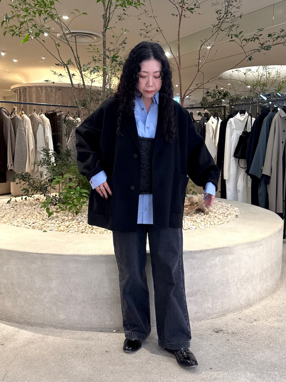 グレー系のニット/セーター、ブラック系のその他アウター、ブルー系のシャツ/ブラウスを着用したレディースの秋コーディネートの4枚目の写真