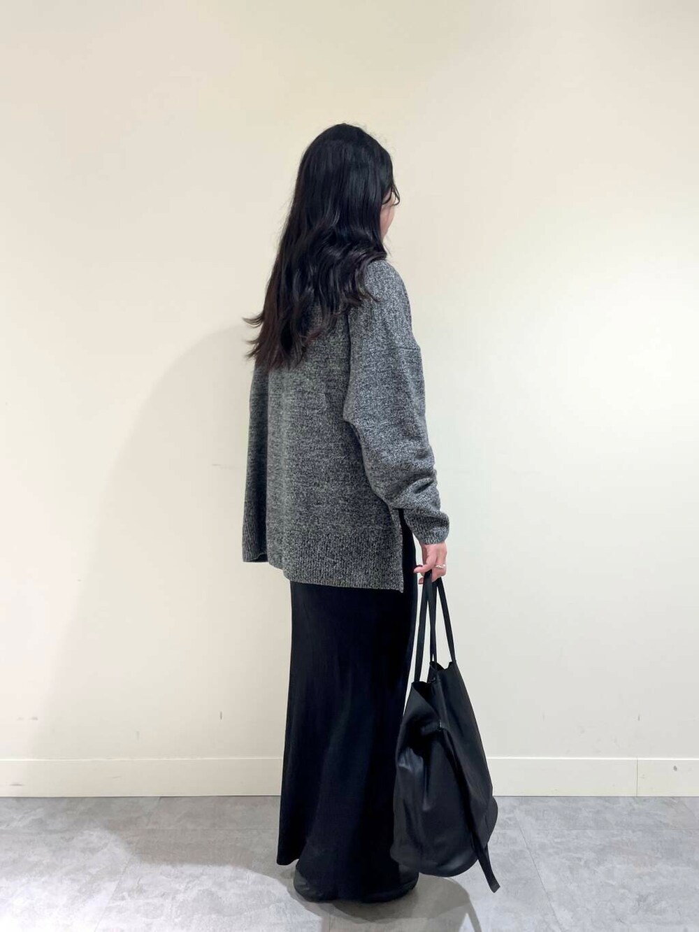 ブラック系のスカート、グレー系のニット/セーター、ブラック系のトートバッグを着用したレディースの冬コーディネートの3枚目の写真