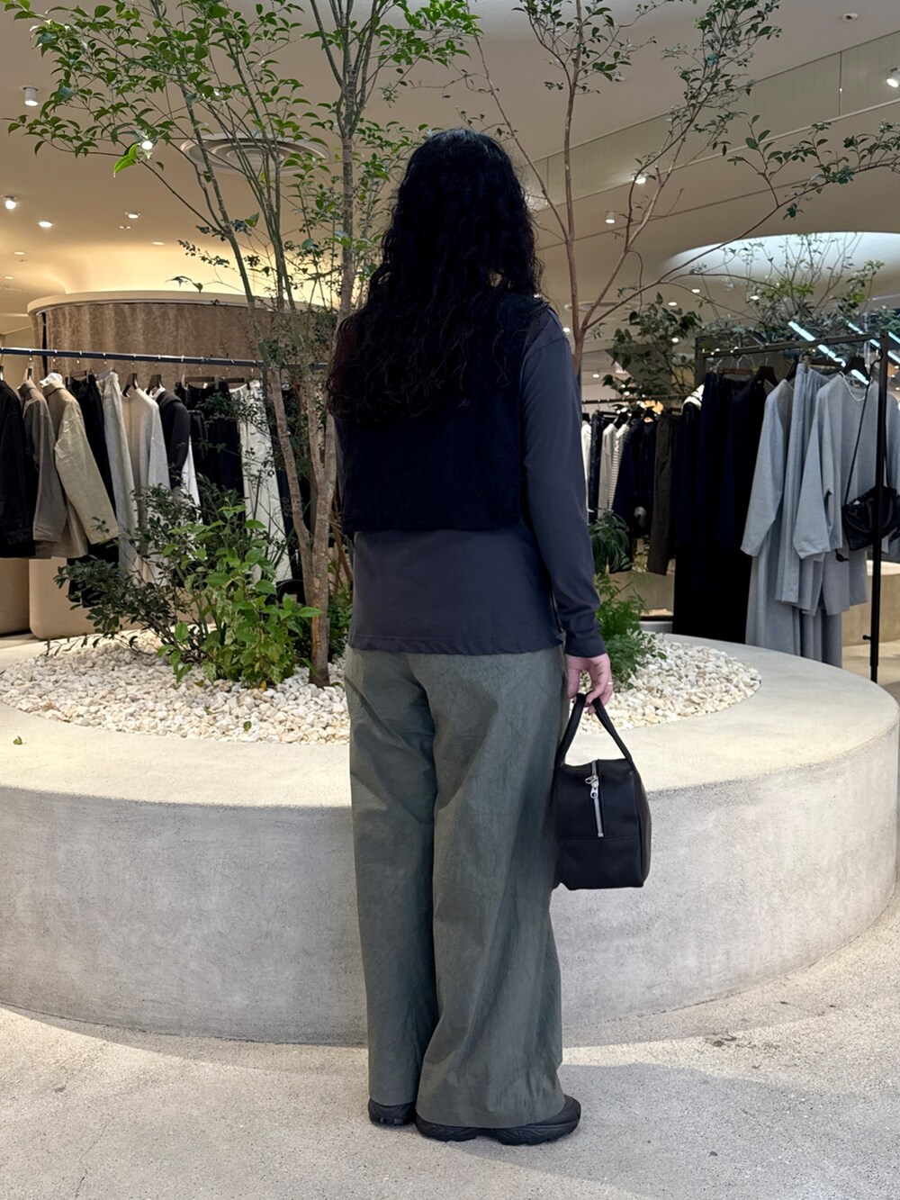 ブラック系のトートバッグ、ブラック系のベスト、グレー系のTシャツ/カットソーを着用したレディースの秋コーディネートの2枚目の写真