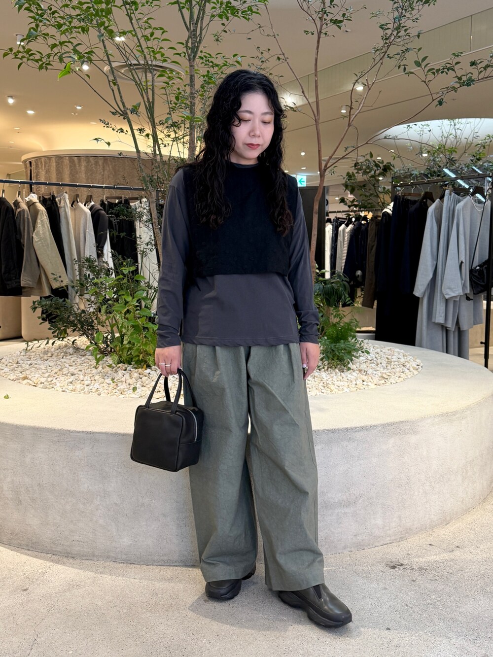 ブラック系のトートバッグ、ブラック系のベスト、グレー系のTシャツ/カットソーを着用したレディースの秋コーディネートの3枚目の写真