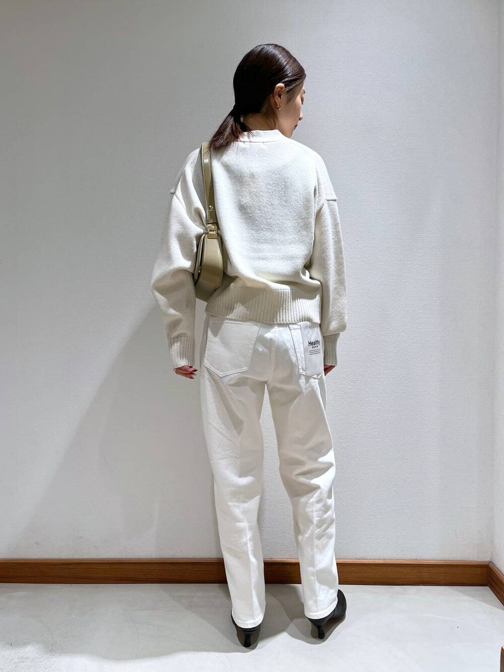 ブラック系のブーツ、ベージュ系のショルダーバッグ、ホワイト系のニット/セーターを着用したレディースの冬コーディネートの6枚目の写真