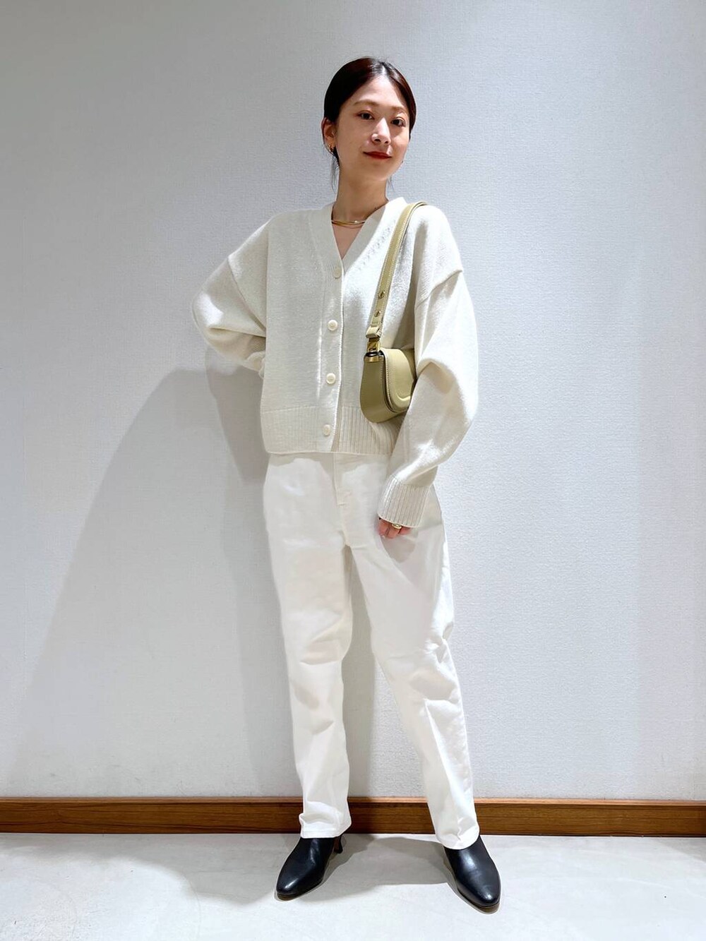 ブラック系のブーツ、ベージュ系のショルダーバッグ、ホワイト系のニット/セーターを着用したレディースの冬コーディネートの5枚目の写真