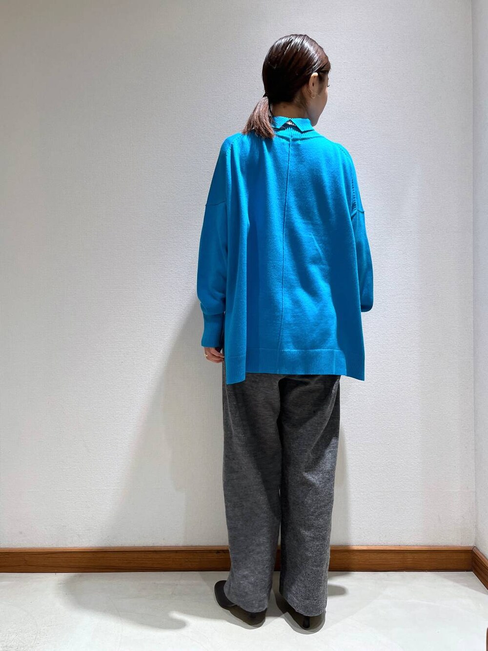 ブラック系のブーツ、グレー系のスラックス、ブルー系のニット/セーターを着用したレディースの冬コーディネートの4枚目の写真